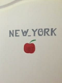 Image of a door with the word New York and an apple painted on it.